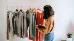 earn from your old clothes - A woman looking at old clothes hanging on cloth hanger