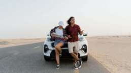 couple sitting in front of a rented car-car rental